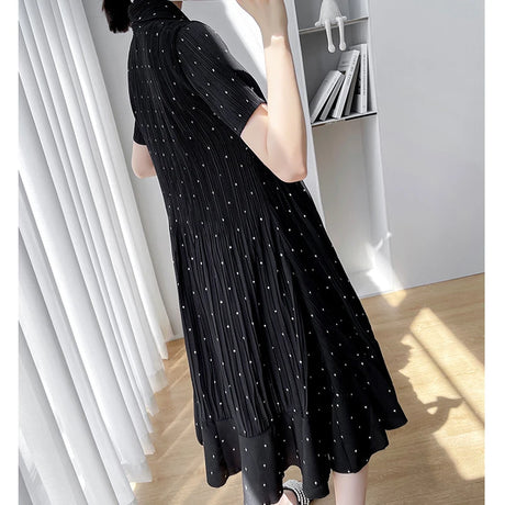 Styling of a black polka dot maternity dress with short sleeves, showcasing a flowy A-line silhouette for summer wear.