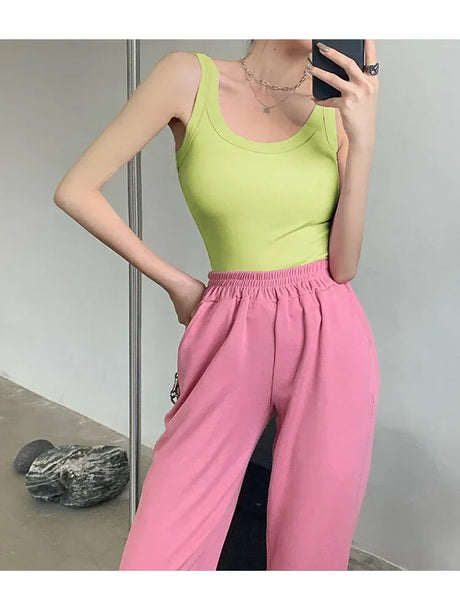 Model wearing a sleeveless lime green ribbed tank top paired with pink joggers, showcasing a trendy streetwear style.