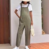 Adjustable maternity overalls in olive green, worn over a white tee, paired with white sneakers and a stylish tote bag.