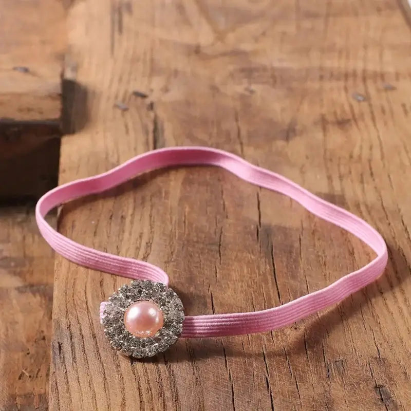 Pink baby headband with pearl embellishment, perfect for newborn photography props and costume accessories.