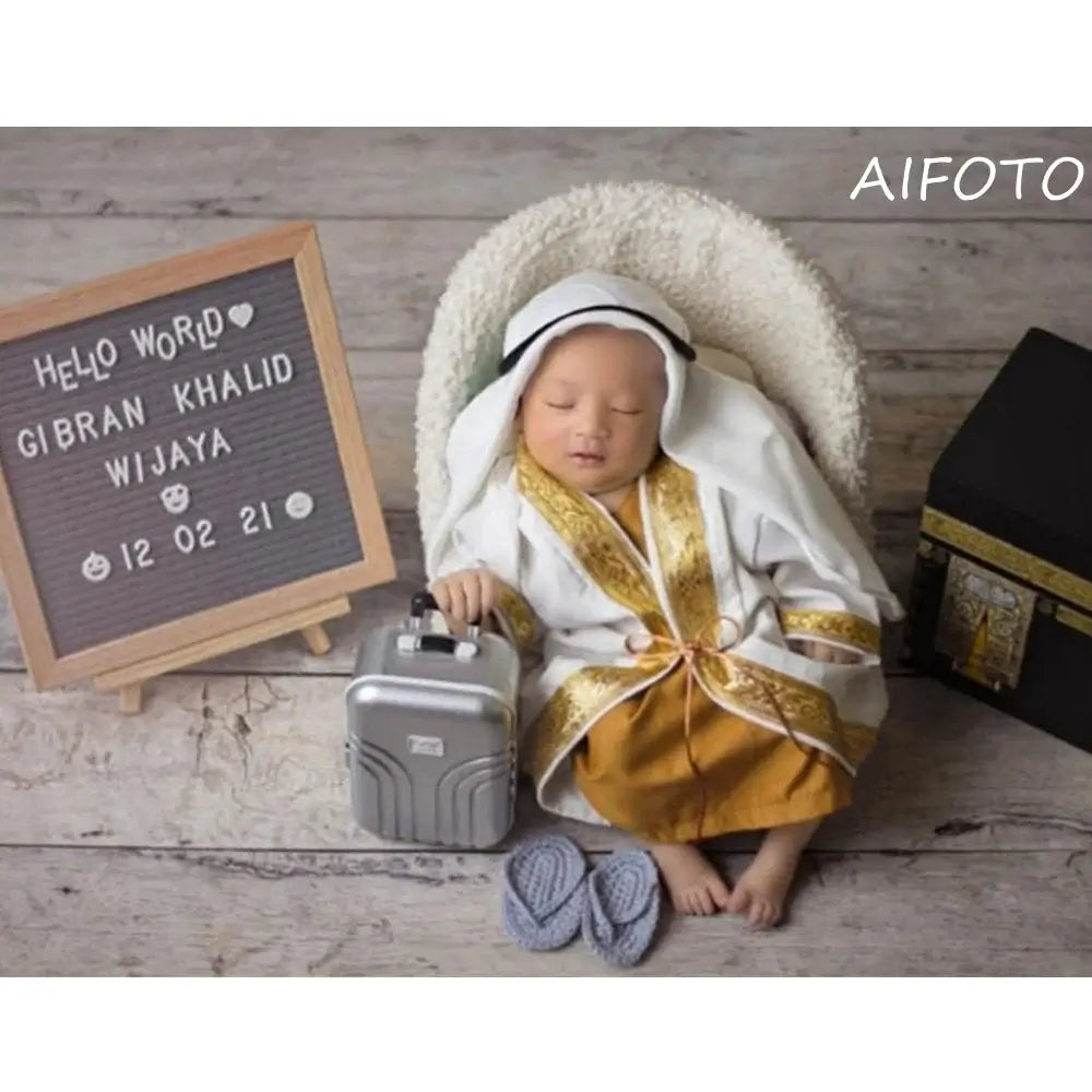 Infant boy dressed in a traditional outfit with a mini suitcase, showcasing BABI Boy Clothes creative design.