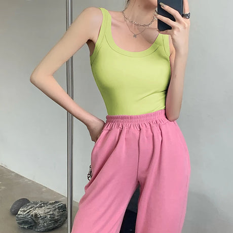 Model wearing a green sleeveless tank top paired with pink pants, showcasing a trendy streetwear style.