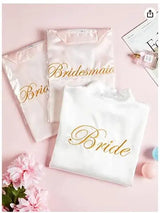 Sets of bridal and bridesmaid robes with elegant gold lettering on a pink background, perfect for wedding celebrations.