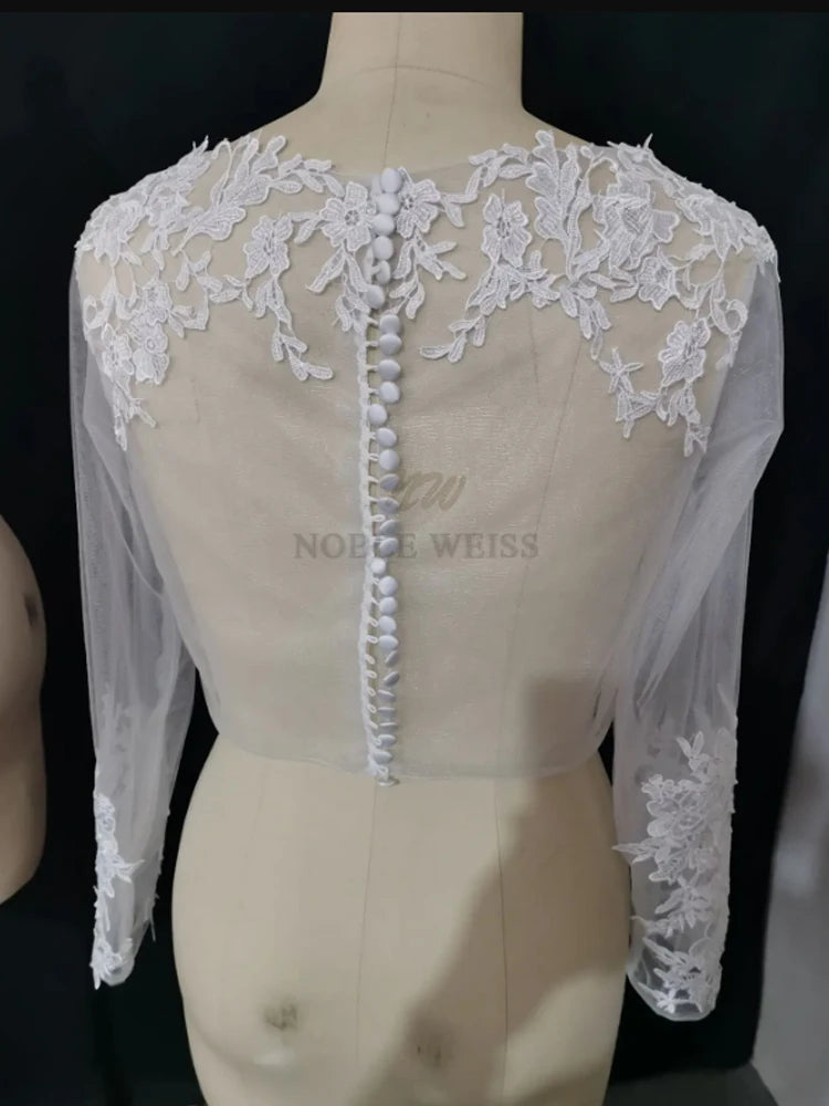 Back view of Lace Bridal Bolero by Noble Weiss, featuring long sleeves and intricate appliques in delicate white fabric.