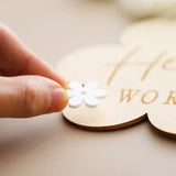 Hand placing a white flower on a wooden baby milestone sign, perfect for capturing precious moments.