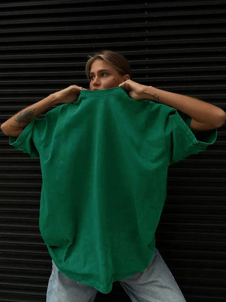 Woman wearing an oversized green casual T-shirt, showcasing a relaxed fit style against a black background.