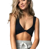 Model wearing DeepVibe™ Deep V Ribbed Crop Top with seamless design, styled with grey sweatpants, showcasing streetwear fashion.