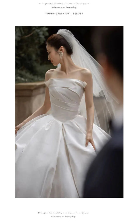 Elegant lace off-shoulder bridal jacket shown with a satin wedding gown, perfect for modern brides seeking timeless beauty.