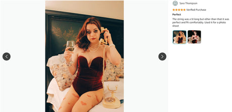 Woman wearing a velvet strapless lace-up bodysuit, holding a drink, posing on a bed for a photo shoot.
