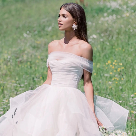 Bride wearing a strapless white gown in a meadow, showcasing elegance and beauty for wedding inspiration.