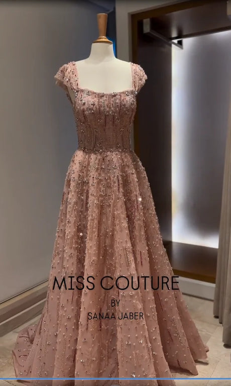 Elegant pink evening gown by Miss Couture, featuring intricate beadwork and a floor-length design.