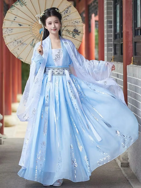 Elegant woman in a blue Tang Dynasty Hanfu costume holding a parasol, showcasing flowing traditional attire.