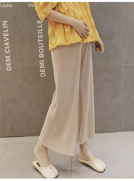 Model wearing Ice Silk Pleated Maternity Pants in beige, paired with a yellow top, showcasing summer style and comfort.