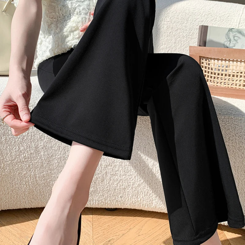 Woman wearing Y2K bootcut maternity pants, showcasing the stylish cropped design in black ice silk fabric.