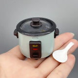 Miniature rice cooker prop in hand, ideal for photography or creative displays, showcasing intricate details and colors.