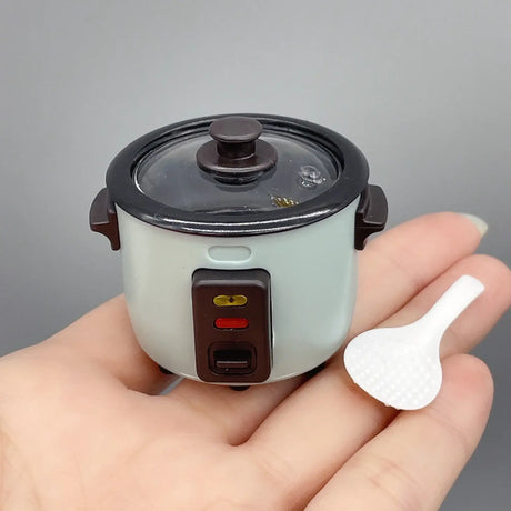 Miniature rice cooker prop in hand, ideal for photography or creative displays, showcasing intricate details and colors.
