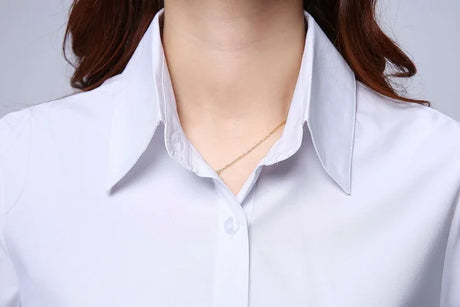 Close-up of a woman's neck wearing a white short sleeve shirt with a turn-down collar and button detail.