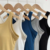 Various colored SlimCotz™ padded cotton spaghetti camis hanging on wooden hangers for summer wear.