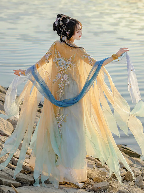 Elegant woman in gradient embroidery Hanfu carnival costume with flowing sleeves by water, showcasing traditional Chinese style.