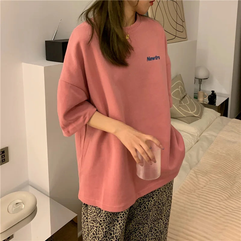 Oversized Harajuku streetwear tee in pink, paired with loose patterned pants, casual home setting.