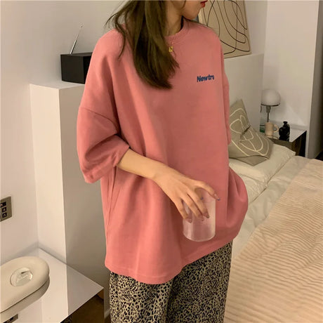 Oversized Harajuku streetwear tee in pink, paired with loose patterned pants, casual home setting.
