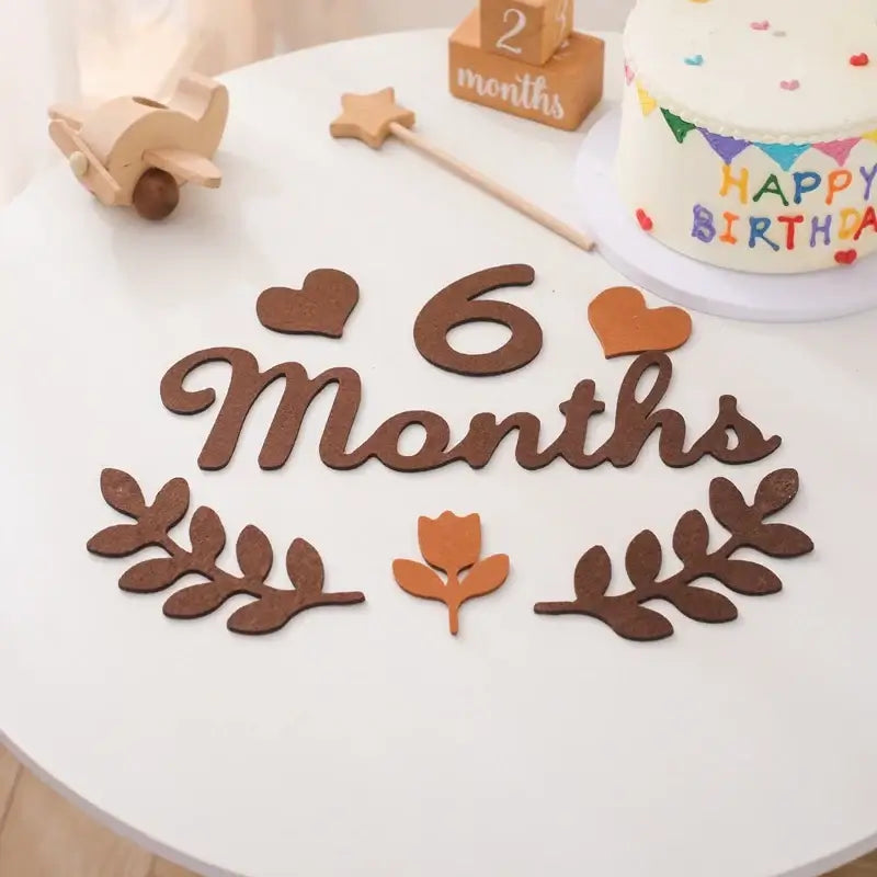 6 Months baby milestone card in soft felt on a decorative table with birthday cake and decorations