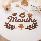 6 Months baby milestone card in soft felt on a decorative table with birthday cake and decorations