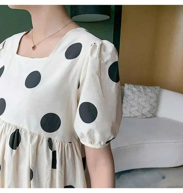 Polka dot loose maternity dress in cream and black, featuring short puff sleeves and a mid-calf length.