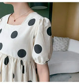 Polka dot loose maternity dress in cream and black, featuring short puff sleeves and a mid-calf length.