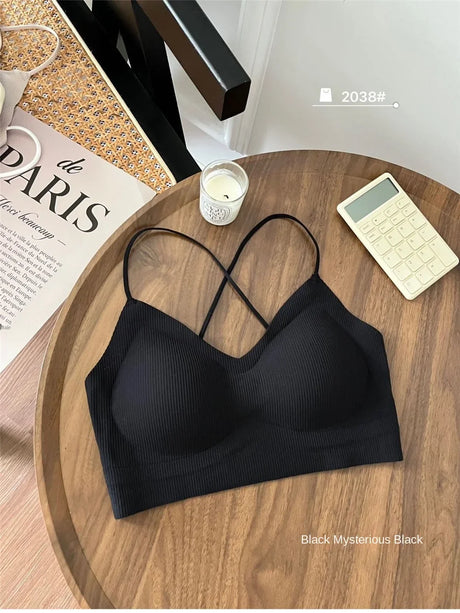 Black padded backless tank top on a wooden table, featuring crisscross straps and a soft ribbed texture.