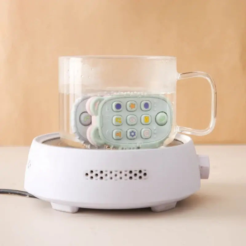 Baby teether gloves in a glass mug on a warming base for effective soothing and teething relief.