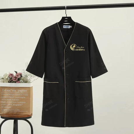 Black beauty uniform with logo, short sleeves, stylish design, ideal for salons and spa professionals.