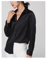 Model wearing a black SatinGrace long sleeve silk shirt with a V-neck and loose fit, styled with white pants.
