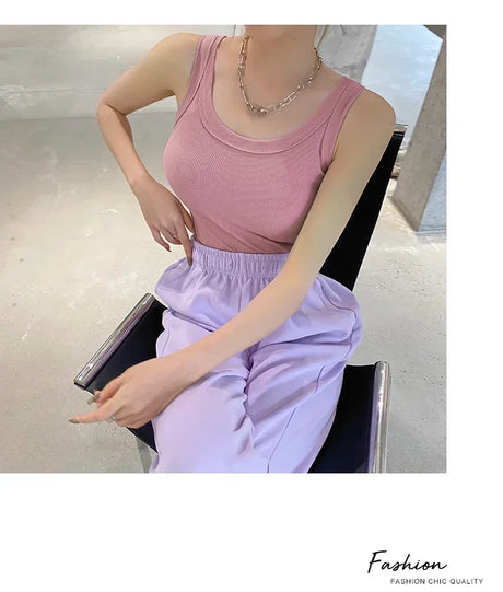 Woman wearing a pink sleeveless vintage ribbed tank top with lilac pants, showcasing a casual streetwear style.