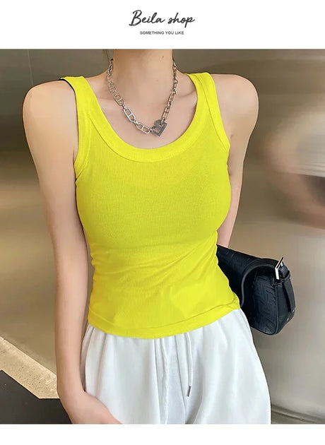 Women wearing a bright yellow ribbed tank top, perfect for streetwear, paired with white pants and a stylish bag.