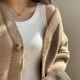Woman wearing a beige cardigan over a white padded cotton spaghetti camisole, showcasing a casual summer outfit.