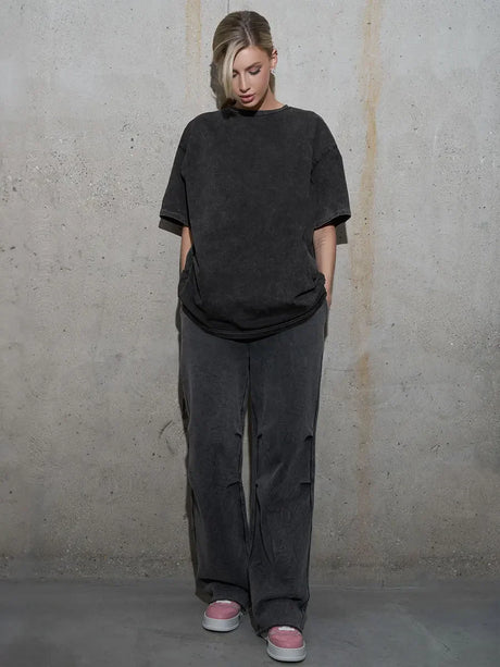 Woman wearing casual black oversized t-shirt and grey pants on a concrete background.