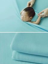 Newborn soft wrap blanket in blue, perfect for baby photography. Soft fabric gently wraps around a sleeping infant.