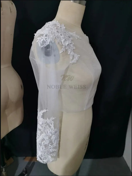Lace Bridal Bolero by Noble Weiss, featuring long sleeves and delicate appliqued design for a stunning bridal look.
