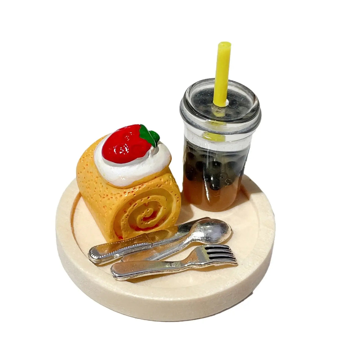 Miniature dessert set featuring a yellow roll cake with strawberries and a drink with a straw on a wooden plate.