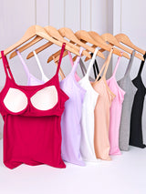 Bralux™ adjustable bra camisoles in various colors hanging on wooden hangers, featuring built-in bras and soft inner layers.