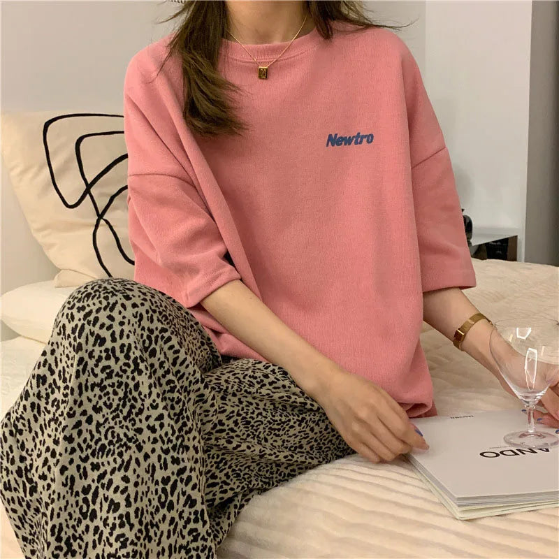 Oversized Harajuku tee in pink with 'Newtro' lettering, styled with leopard print pants, perfect for casual women's streetwear.