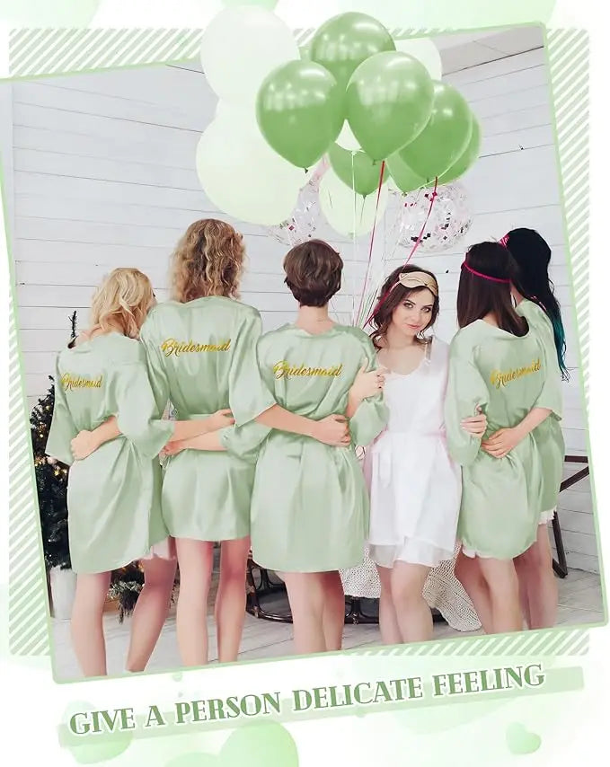 Bridesmaids in matching green satin kimonos at a wedding shower, holding balloons and posing together.