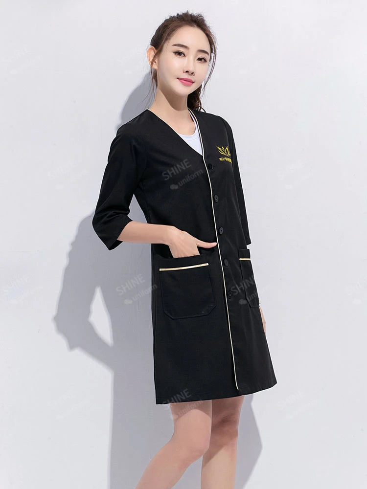 Black beauty uniform with short sleeves and pockets, ideal for salons and spas. Stylish and functional design.