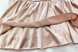Close-up of soft, shimmering fabric in a light pink color, showcasing gathered ruffle detail for a stylish crop top.