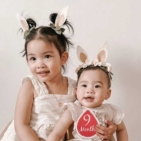 Two girls wearing bunny headbands celebrating milestone at 9 months, perfect for newborn photography.