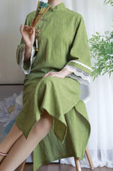 Green cotton jacquard cheongsam dress with lace details and fan, showcasing traditional style and comfort.