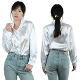 SilkAura™ imitation silk blouse in white, featuring a loose fit and button closure, paired with high-waisted jeans.