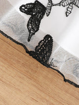 Close-up of lace butterfly decoration on a toddler girl dress hem, showcasing intricate black lace details.