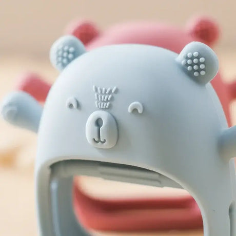 Cute baby teether glove in blue with bear design, made from soft, safe, non-toxic silicone for teething relief.